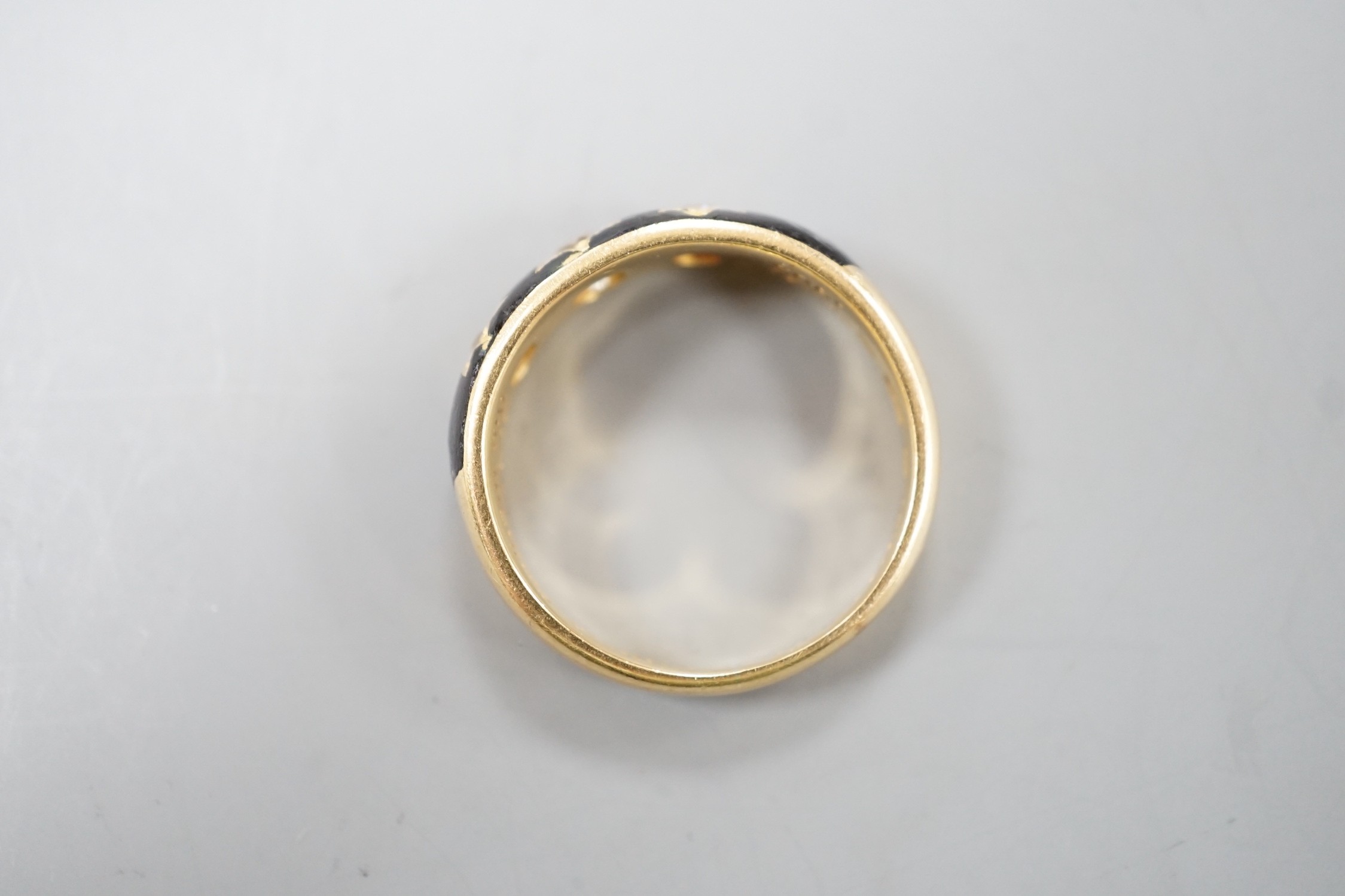 An Edwardian 18ct, black enamel and three stone gypsy set diamond mourning ring, size Q/R, gross weight 6.6. grams, the interior shank inscribed 'Sacred to the memory of my beloved husband'.